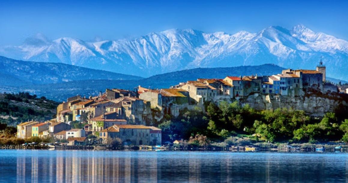 Urlaub in Occitanie Stadt vor Bergen und Wasser